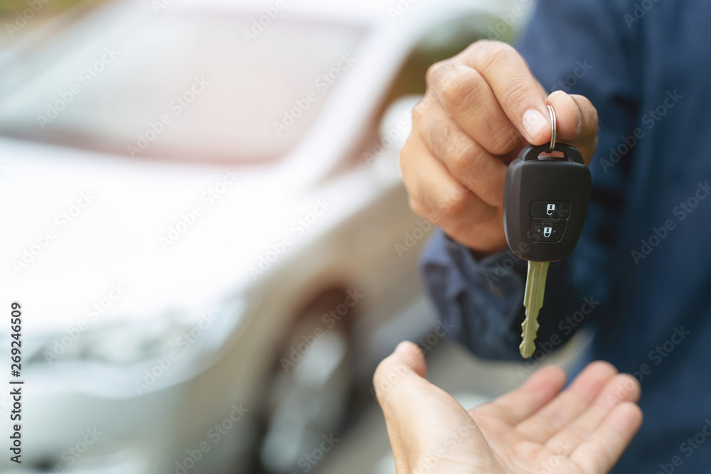 Car key, businessman handing over gives the car key to the other woman on car background. - obrazy, fototapety, plakaty 