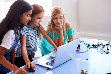 Three Female Students Building And Programing Robot Vehicle In After School Computer Coding Class