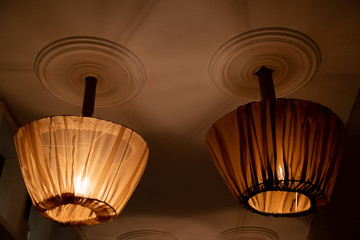 Two ceiling lamps with retro style lampshades draped with tulle covers. Lamp shades sewed from transparent brown tulle. Textile decor for chandeliers.