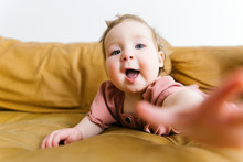 Baby Girl Reaching For Camera On Sofa