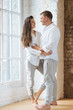 © Ivan Ozerov/Tetra Images - Smiling couple embracing by window
