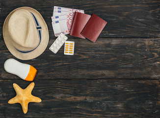 flat lay of staff for summer vacation on dark wooden background. summer travel concept with copy space