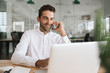 © mavoimages - Smiling businessman using a laptop and talking on his cellphone