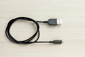 Fototapete - black micro usb data transfer cable at wooden background.