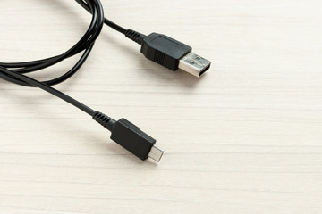 Fototapete - black micro usb data transfer cable at wooden background.