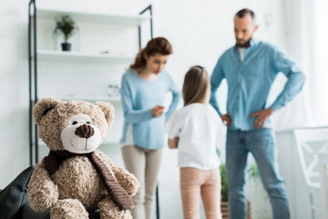 selective focus of teddy bear near quarreling family at home