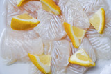 Fototapeta Kuchnia - Fresh raw fish fillet piece with lemon on white plate background - Close up pangasius dolly fish meat
