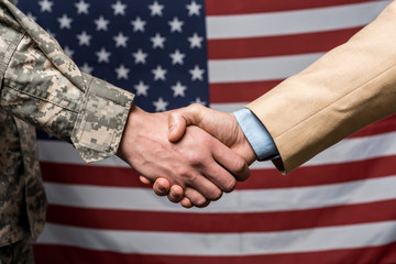 Wall Mural - Selective focus military men shaking hands near American flag
