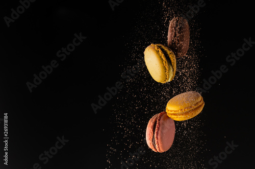 Photographie Colored macaroons, French cookies, colored levitates with cocoa powder on a blac