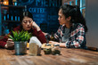 young asian woman consoling depressed best friend. sad lady sitting at bar counter and leaning cheek face on hand while being comfort. upset female heart broken get drunk drink beer in pub at night.