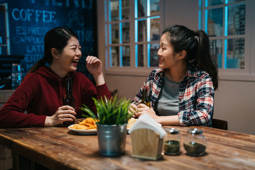 Happy girlfriends women group drinking beer at brewery bar restaurant in dark night. Friendship concept with young female friends enjoying time and having genuine fun at cool vintage pub midnight