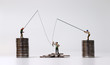 Miniature people fishing and piles of coins. The concept of economic inequality.