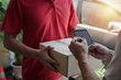 © Vittaya_25 - home delivery service man in red uniform and young man customer appending signature in digital mobile phone receiving parcel post box from courier at home, express delivery and online shopping concept