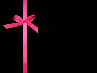 Wall Mural - Bows from pink satin ribbon vertically on black background with copy space. Greeting card concept