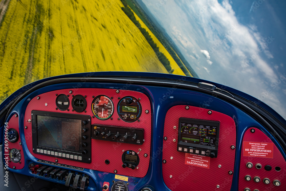flying propeller plane dashboard in the cabin over a rape field Altimeter magnetic compass
