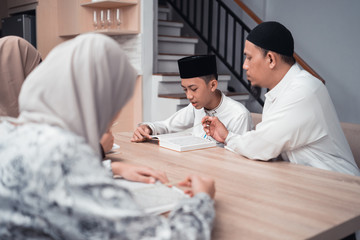 Wall Mural - portrait of a muslim father teaching his son how to read quran