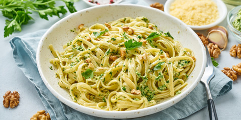 Poster - Banner with pesto pasta, bavette with walnuts, parsley, garlic, nuts, olive oil. Side view, long side, blue background.