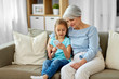 family, generation and technology concept - grandmother and granddaughter with smartphone at home