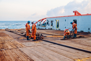 Anchor-handling Tug Supply AHTS vessel crew preparing vessel for static tow tanker lifting. Ocean tug job. AB and Bosun on deck. They pull towing wire