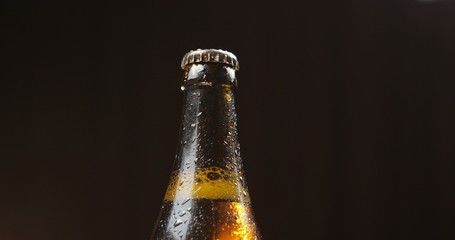 Bottle of cold beer on a black background. Condensate