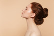 Young redhead woman posing isolated over beige wall background.