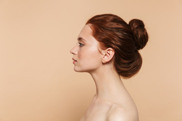 Wall Mural - young redhead woman posing isolated over beige wall background.