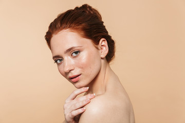 Poster - Young redhead woman posing isolated over beige wall background.