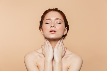 Wall Mural - amazing young redhead woman posing isolated over beige wall background.