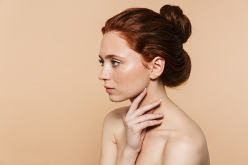 Wall Mural - young redhead woman posing isolated over beige wall background.