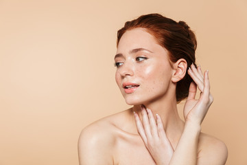 Wall Mural - Amazing young redhead woman posing isolated over beige wall background.