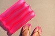 © Tetiana - Background with an inflatable pillow and feet in a slaps on the sand.
