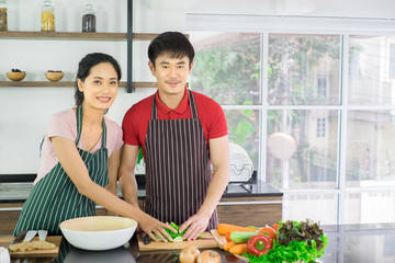 Asian young couple. Are standing smiling cooking in the kitchen at home. prepare salad for food together happily.