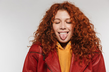 Portrait of funny redhead woman 20s wearing leather jacket smiling and sticking out her tongue