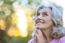 Close Up Portrait Of Cute Senior Woman Praying Outdoors