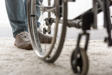 Wall Mural - cropped view of man standing on carpet near wheelchair