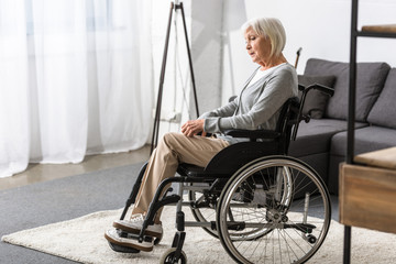 Wall Mural - disabled senior woman sitting in wheelchair and looking away