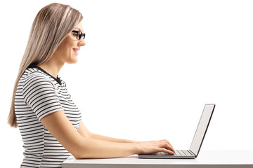 Poster - Young blond woman sitting and working on a laptop computer