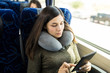 © AntonioDiaz - Woman reading an e-book while traveling by bus and wearing a neck pillow
