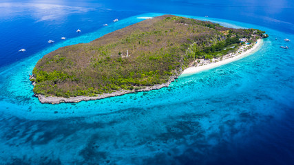 Aerial view of the Sumilon island, sandy beach with tourists swimming in beautiful clear sea water of the Sumilon island beach, Oslob, Cebu, Philippines.