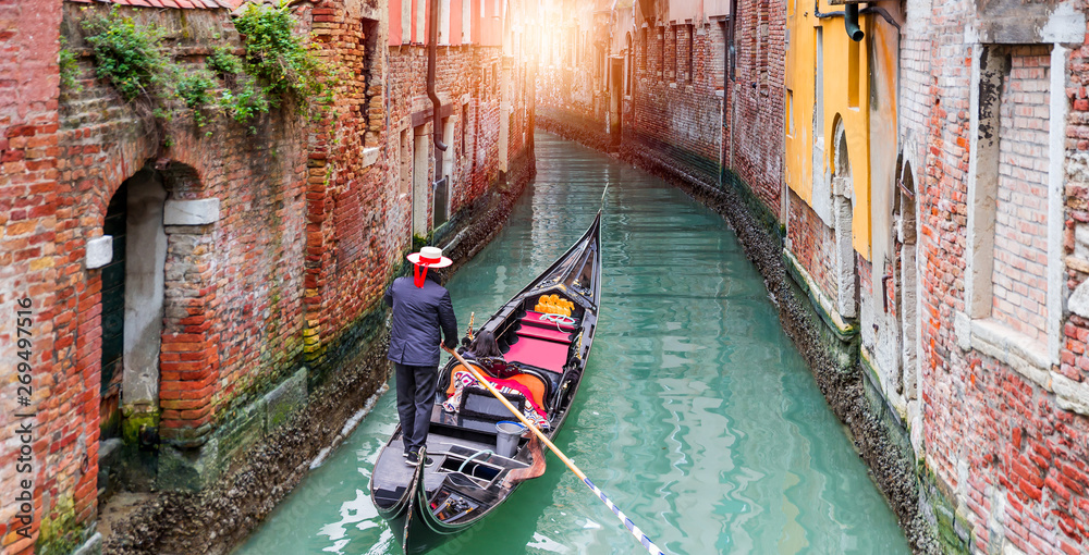 Venetian gondolier punting gondola through green canal waters of Venice Italy - obrazy, fototapety, plakaty 