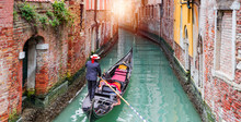 Venetian Gondolier Punting Gondola Through Green Canal Waters Of Venice Italy