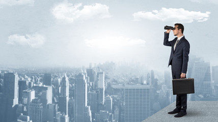 Wall Mural - businessman looking forward to a city with binoculars from skyscraper concept