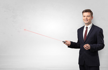 Young businessman with laser pointer and copyspace white wall
