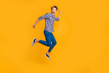 Full length body size view portrait of nice attractive cheerful cheery optimistic guy in checked shirt having fun running fast hurry rush isolated over bright vivid shine yellow background