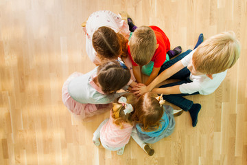 Canvas Print - Children sitting together on a floor in a close circle