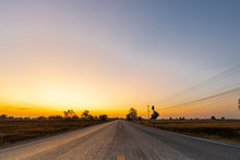 Golden Beautiful Sunrise Clear With Dry Grass Fields And Long Asphalt Road & Electric Pole In The Countryside At Morning On Quiet Day