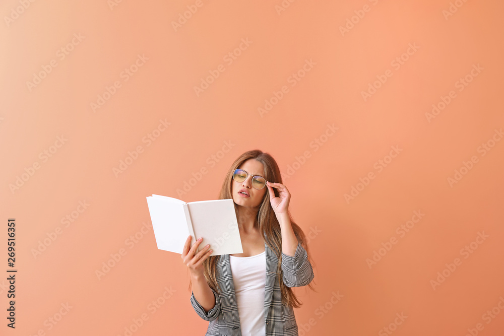 Beautiful young woman with book on color background