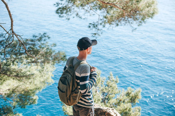 Wall Mural - Tourist with a backpack near the sea. Travel alone. Looks into the distance.