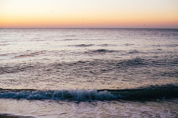 Wall Mural - Beautiful sea waves foam closeup and pink sky in sunrise light on tropical island. Waves in ocean at sunset. Tranquil calm moment. Summer vacation. Copy space