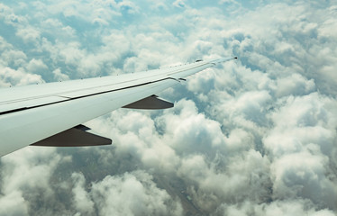 Wall Mural - Wing of plane over white clouds. Airplane flying on blue sky. Scenic view from airplane window. Commercial airline flight. Plane wing above clouds. Flight mechanics concept. International flight.